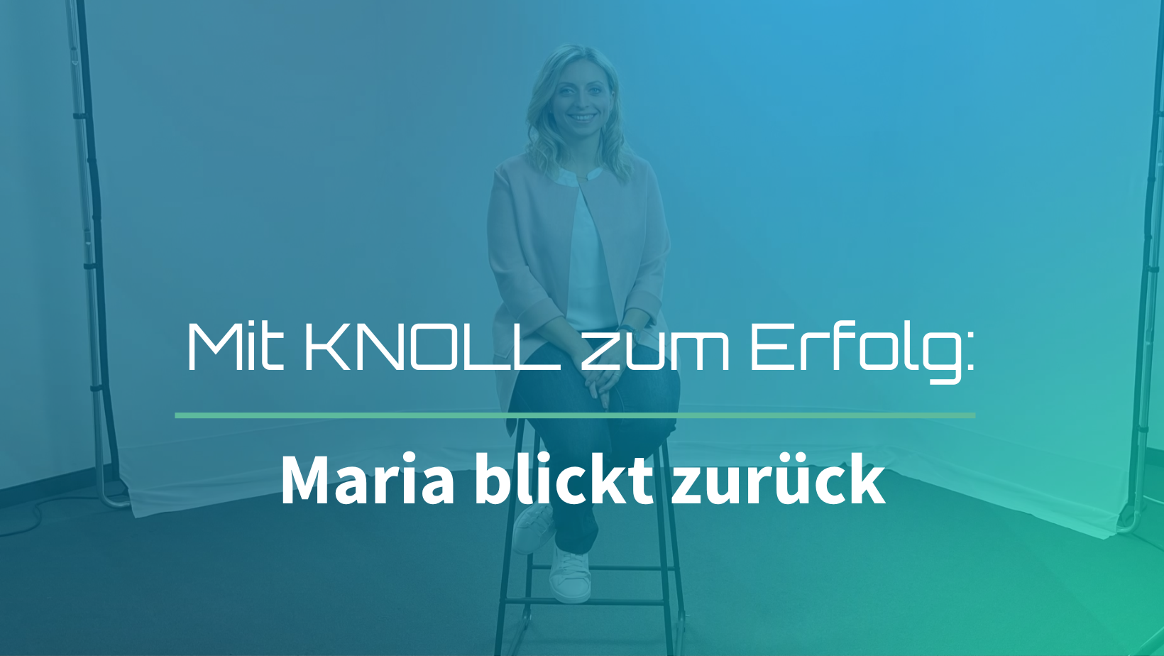 Frau sitzt auf einem Hocker vor blau-grünem Studiohintergrund und lächelt in die Kamera. Text im Bild: Mit KNOLL zum Erfolg: Maria blickt zurück – Thumbnail eines Videos zur persönlichen Rückschau einer Absolventin der Steuerberaterprüfung mit KNOLL.