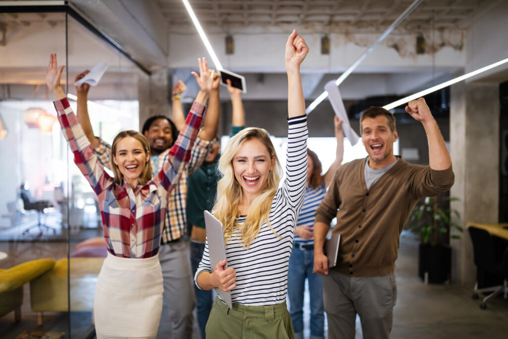 Symbolbild für bestandene Prüfungen oder erfolgreiche Weiterbildungen: Junge Menschen jubeln, lächeln und halten Unterlagen in der Hand.